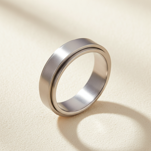 Anillo de acero inoxidable relajante sobre fondo crema blanco